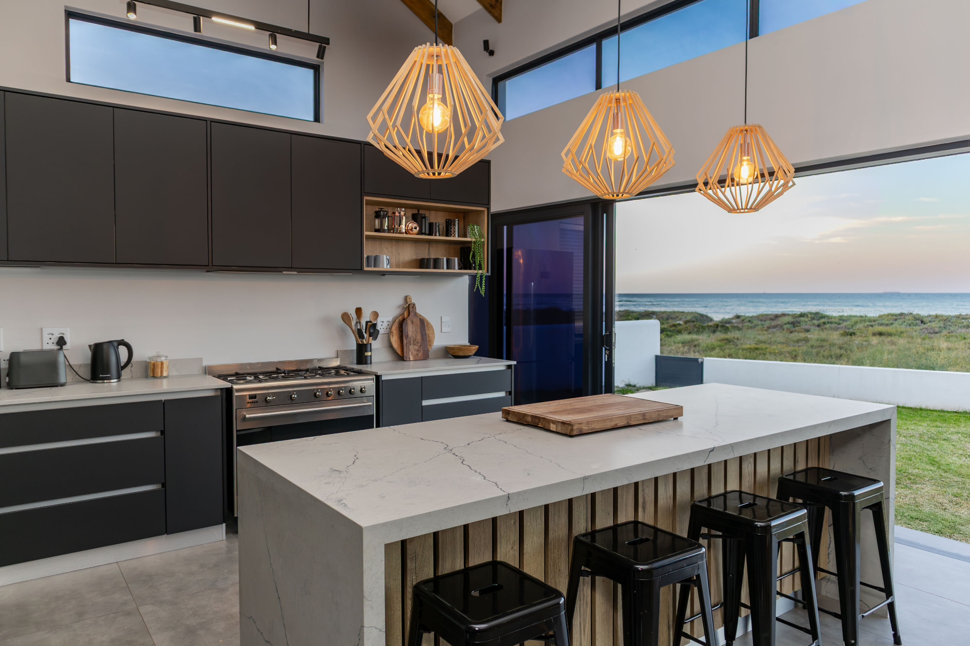 Kitchen island and open glass doors framing the ocean at sunset at Starfish Beach Villa